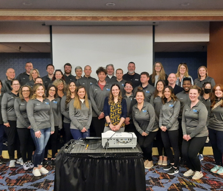A group of people in grey quarter zips smiling at the camera