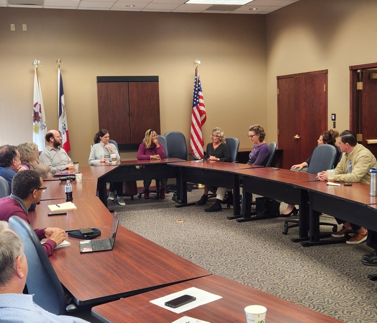 Group of people around wooden tables in a meeting room
