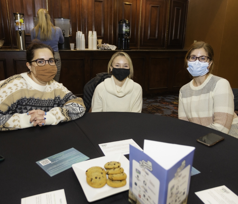 three women wearing masks sitting at a table