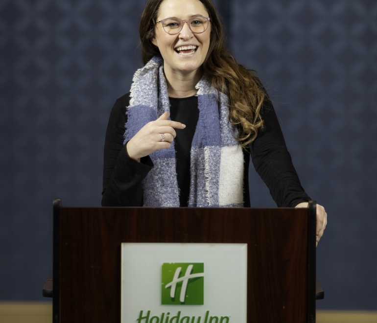 woman in glasses speaking at a podium