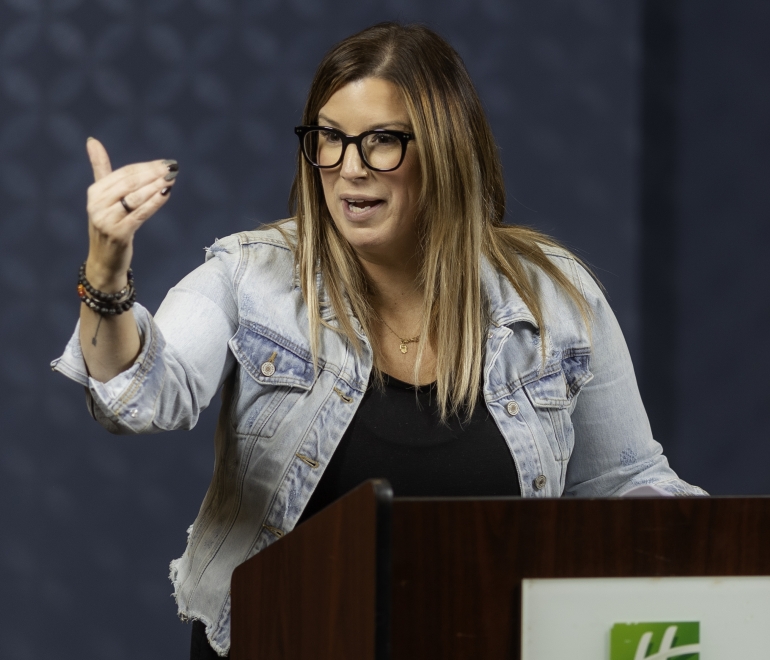 woman in glasses speaking at a podium