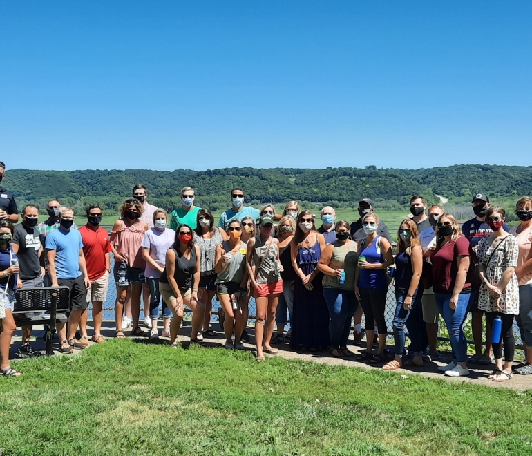 A group of people wearing masks posing for the camera in front of the Mississippi River at Eagle Point Park