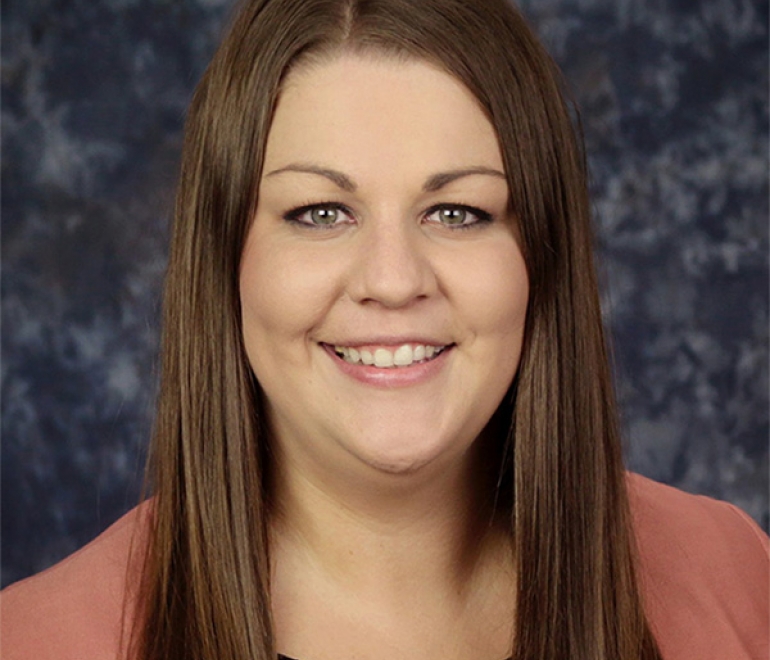 headshot of young woman with brown hair and pint shirt