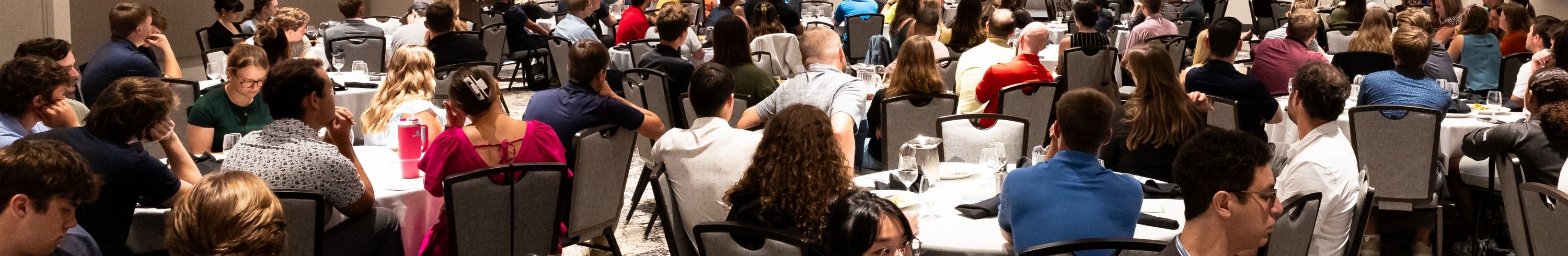Group of Young Professionals looking toward a presenter and screen.