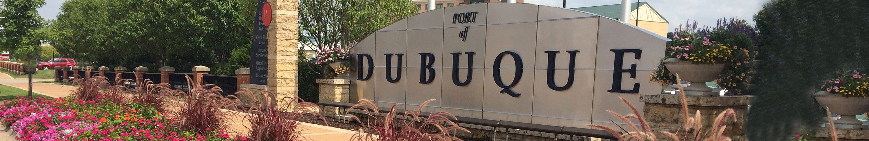 a stone wall with Port of Dubuque written across the front surrounded by shrubs.